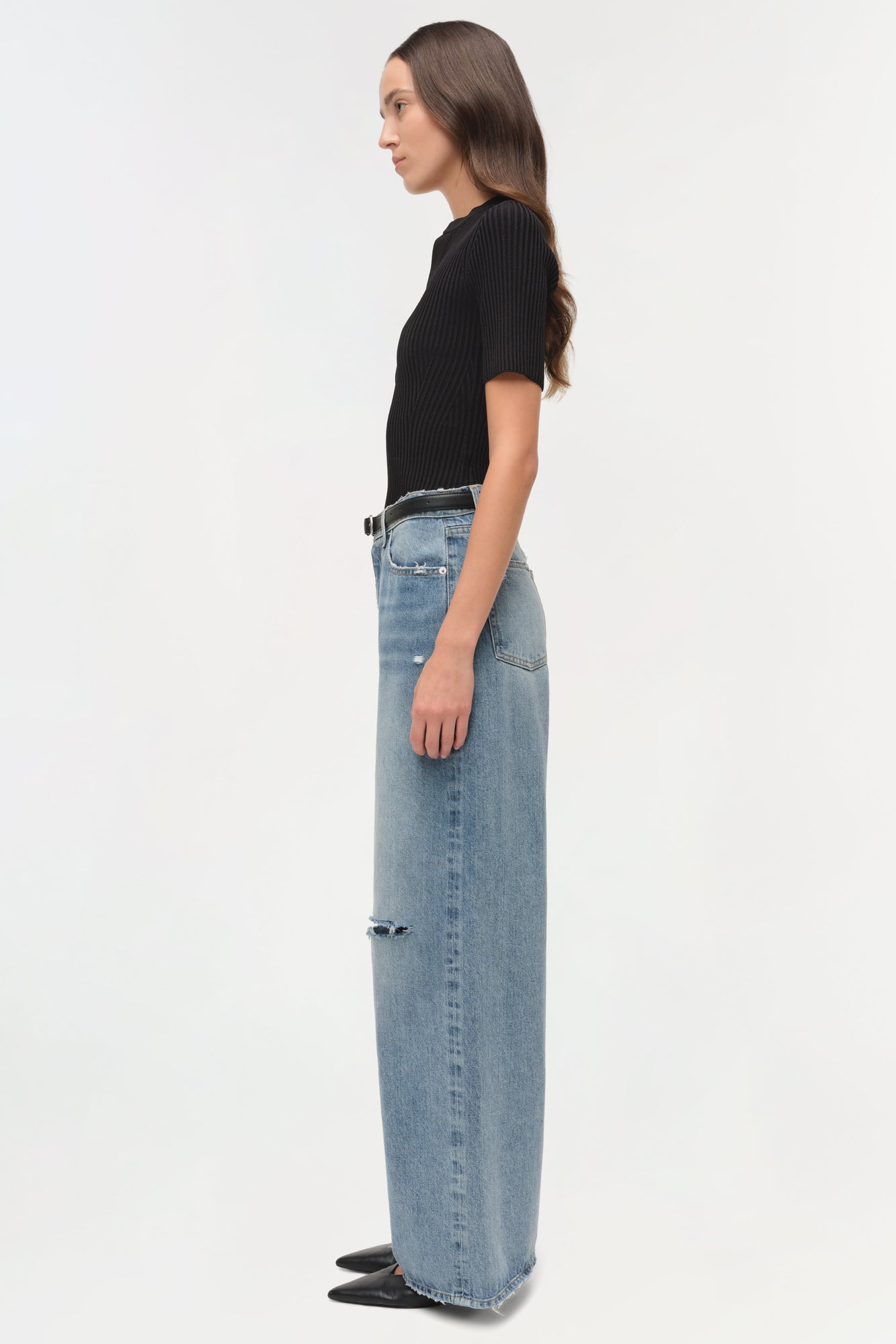 Woman wearing light blue denim straight crop pants with ripped details and a black ribbed short-sleeve top.