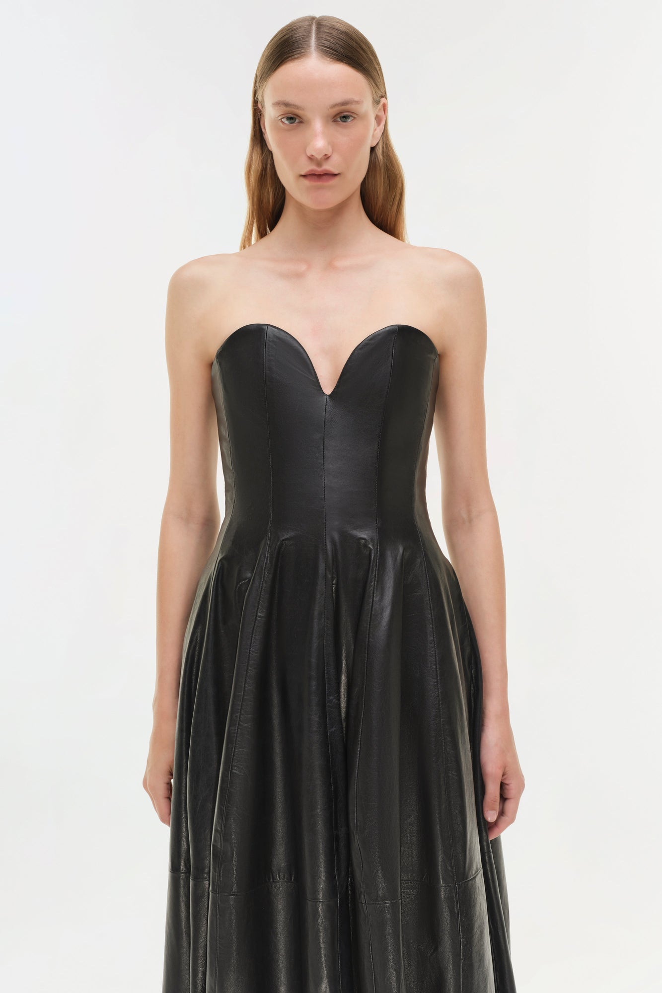 Black leather strapless bustier gown with sweetheart neckline and pleated full skirt.