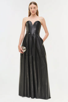 Black leather strapless bustier gown with sweetheart neckline and full skirt, worn with silver clutch.