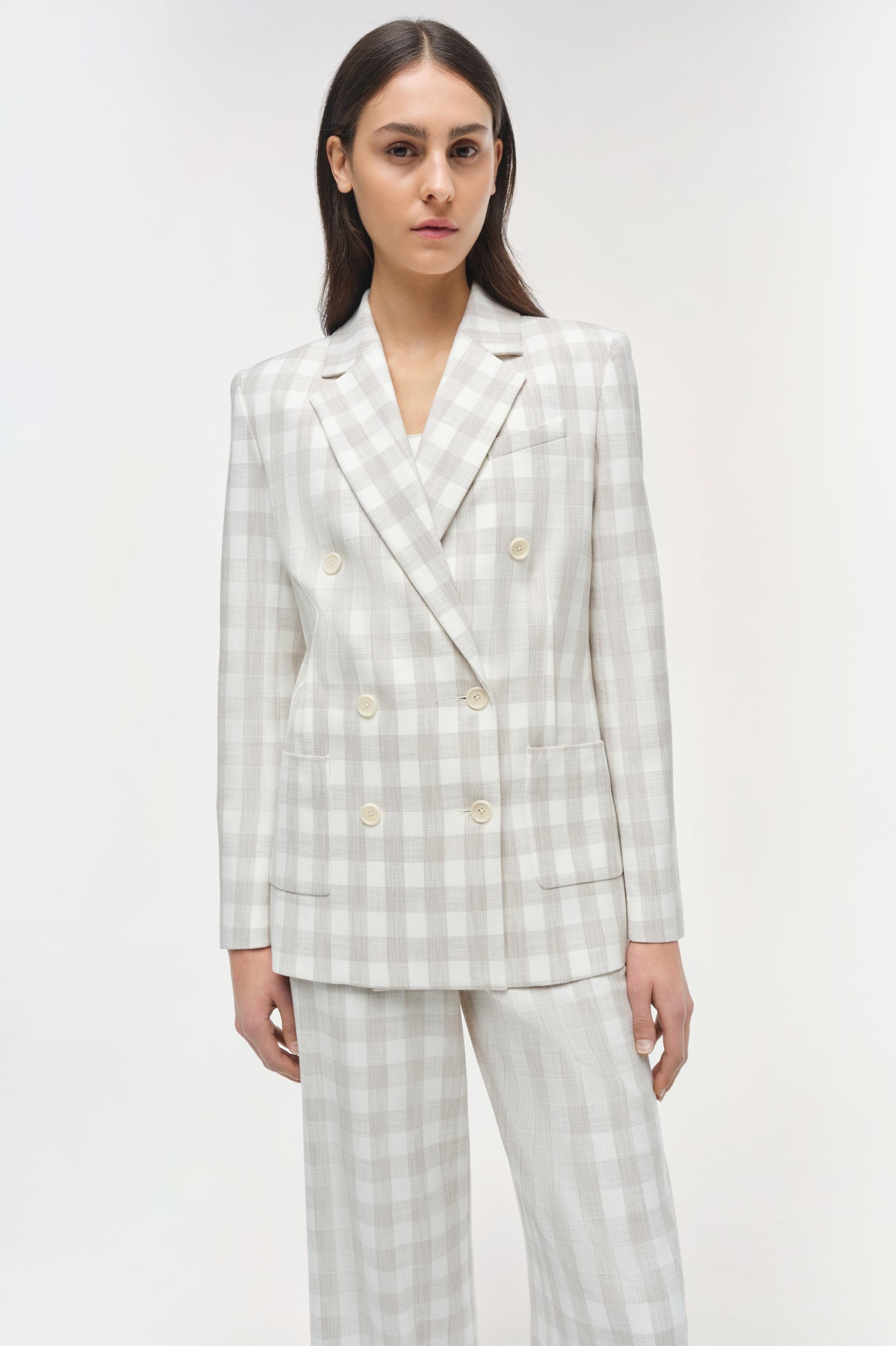 Beige and white check double-breasted blazer with peaked lapels and mother-of-pearl buttons.