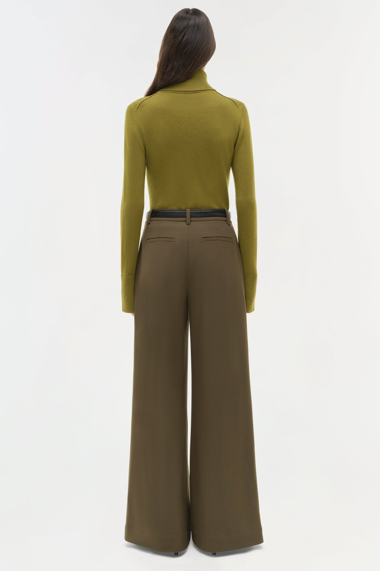 Woman wearing olive turtleneck and khaki wide-leg pants with belt, back view.