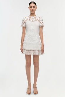 White lace dress with short sleeves, paisley patterned bodice, and tiered lace skirt.