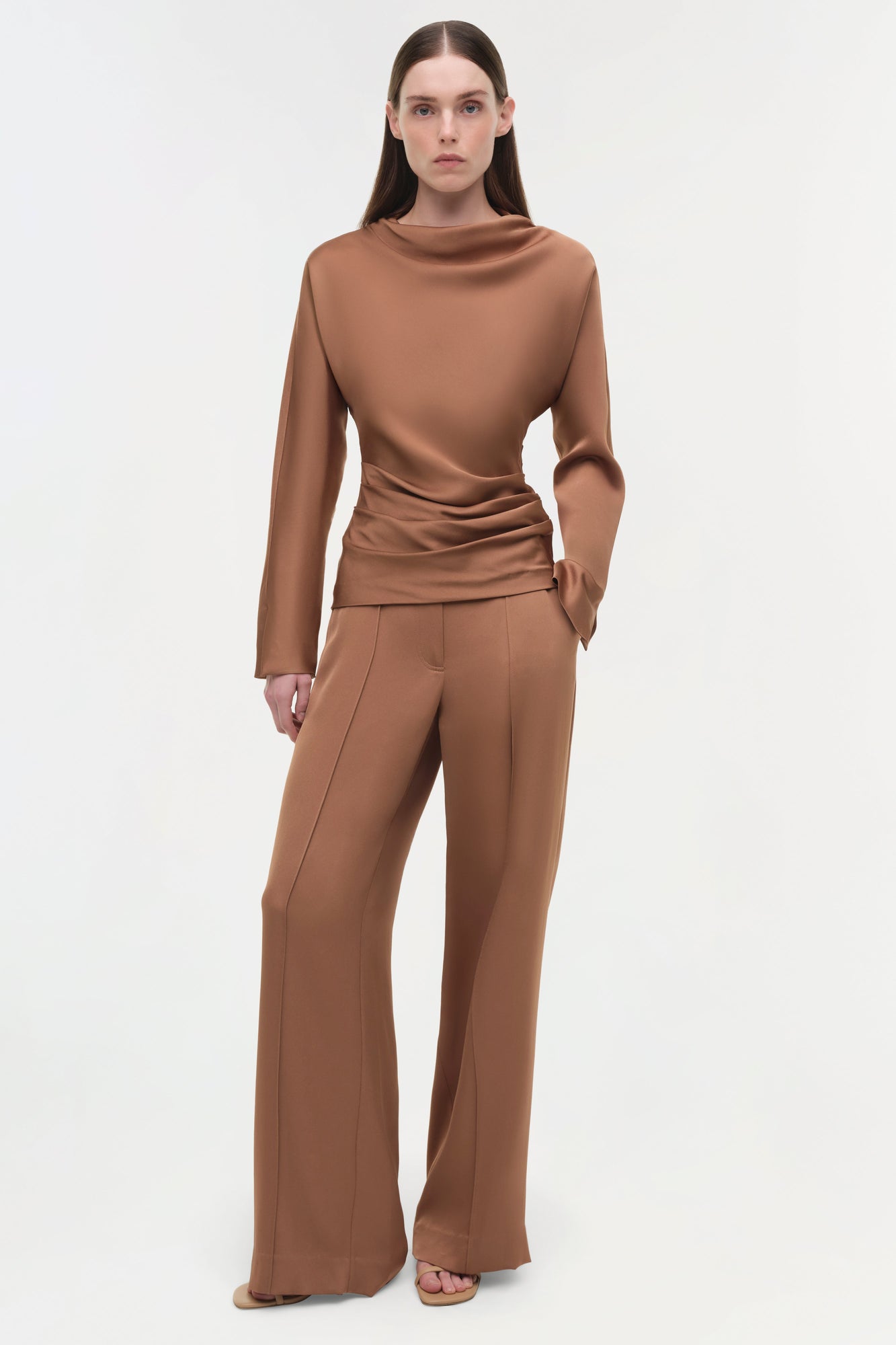 Woman wearing camel-colored satin wide-leg pants with a matching long-sleeve turtleneck top.