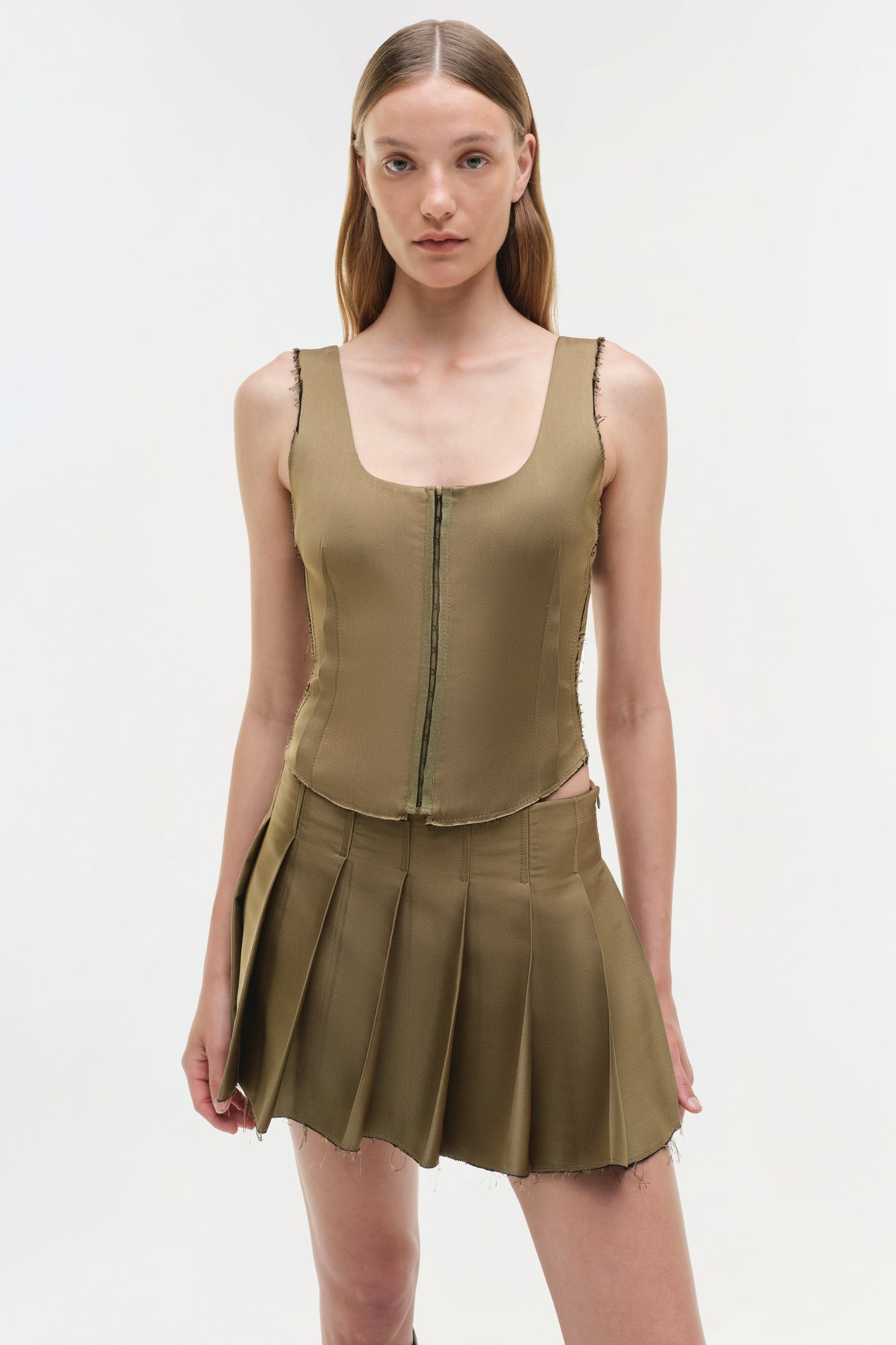 Olive green sleeveless bustier top with front zip closure and raw seam edges.