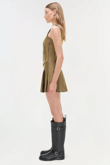 Khaki pleated mini skort with fitted waistband shown on model wearing black boots.