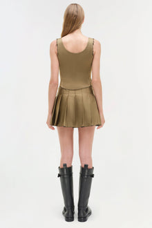 Olive pleated mini skort with sleeveless tank top, styled with black knee-high boots.