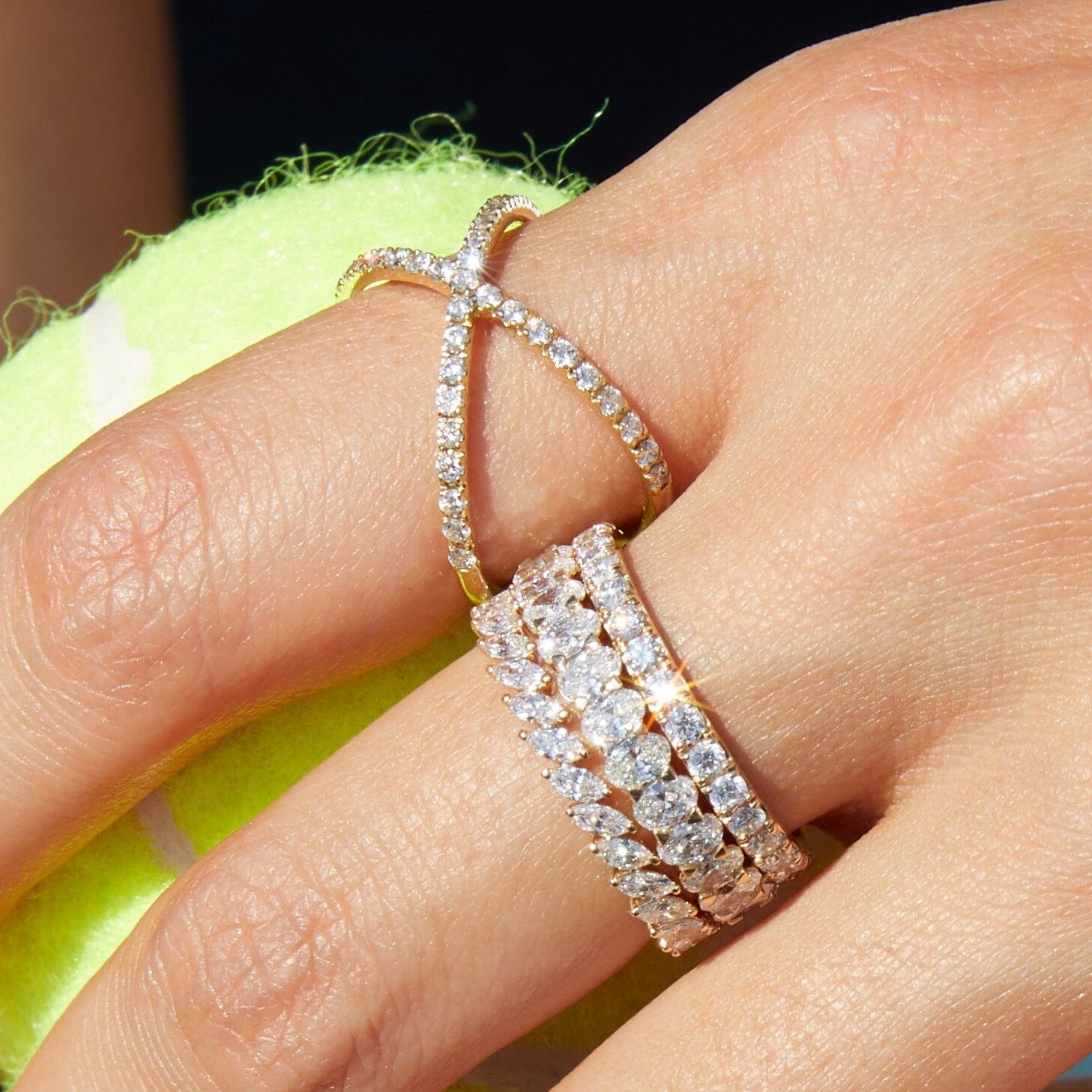 Lifestyle Model Close-up of a woman's hand resting on a tennis ball, wearing multiple gold and diamond rings