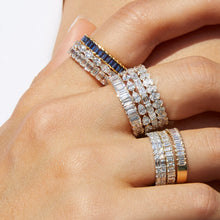 Lifestyle Model Close-up of a woman's hand wearing multiple stacked gold rings featuring diamonds and blue stones