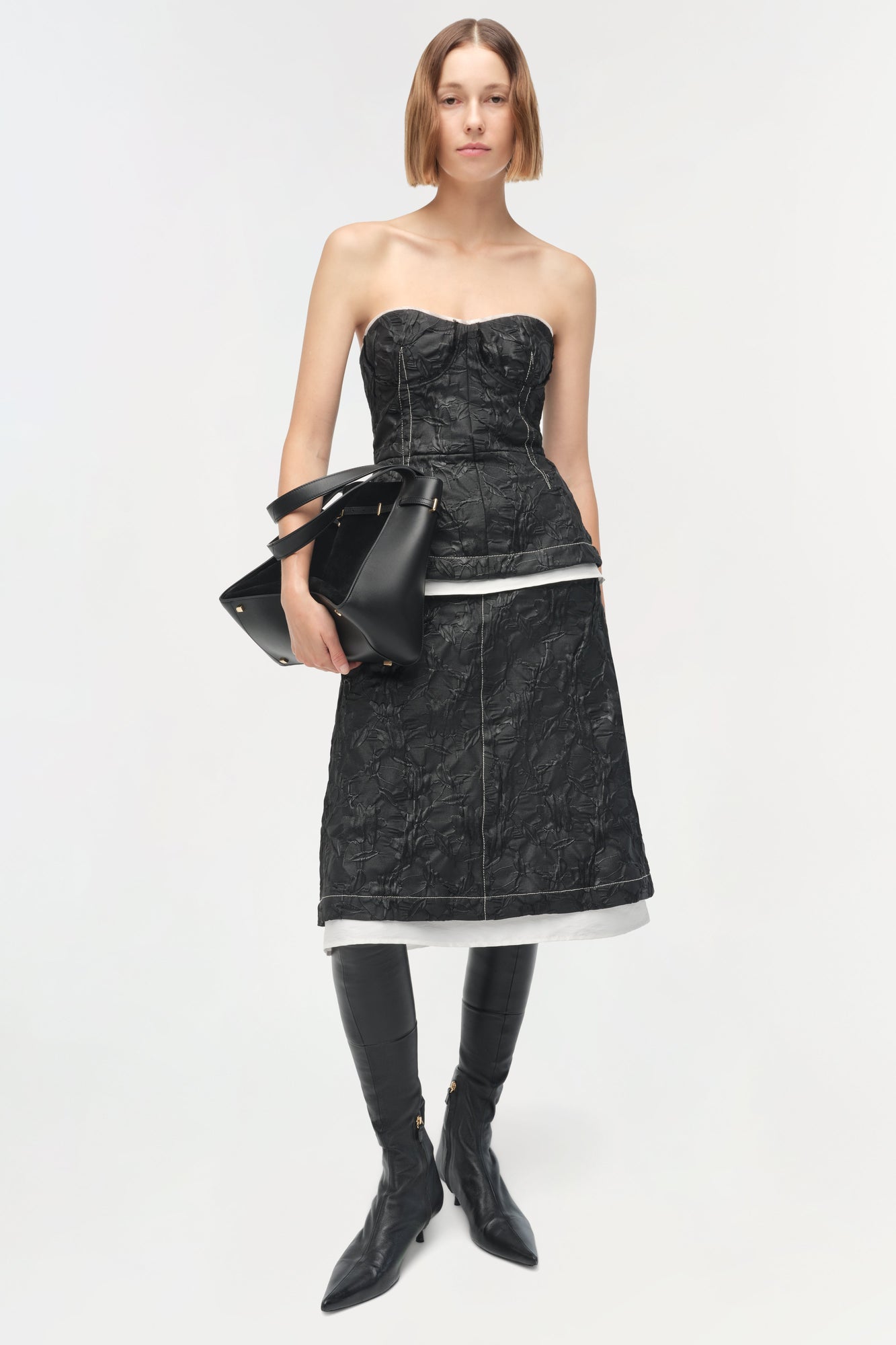 Black jacquard midi skirt with white trim hem, styled with strapless top and black boots.