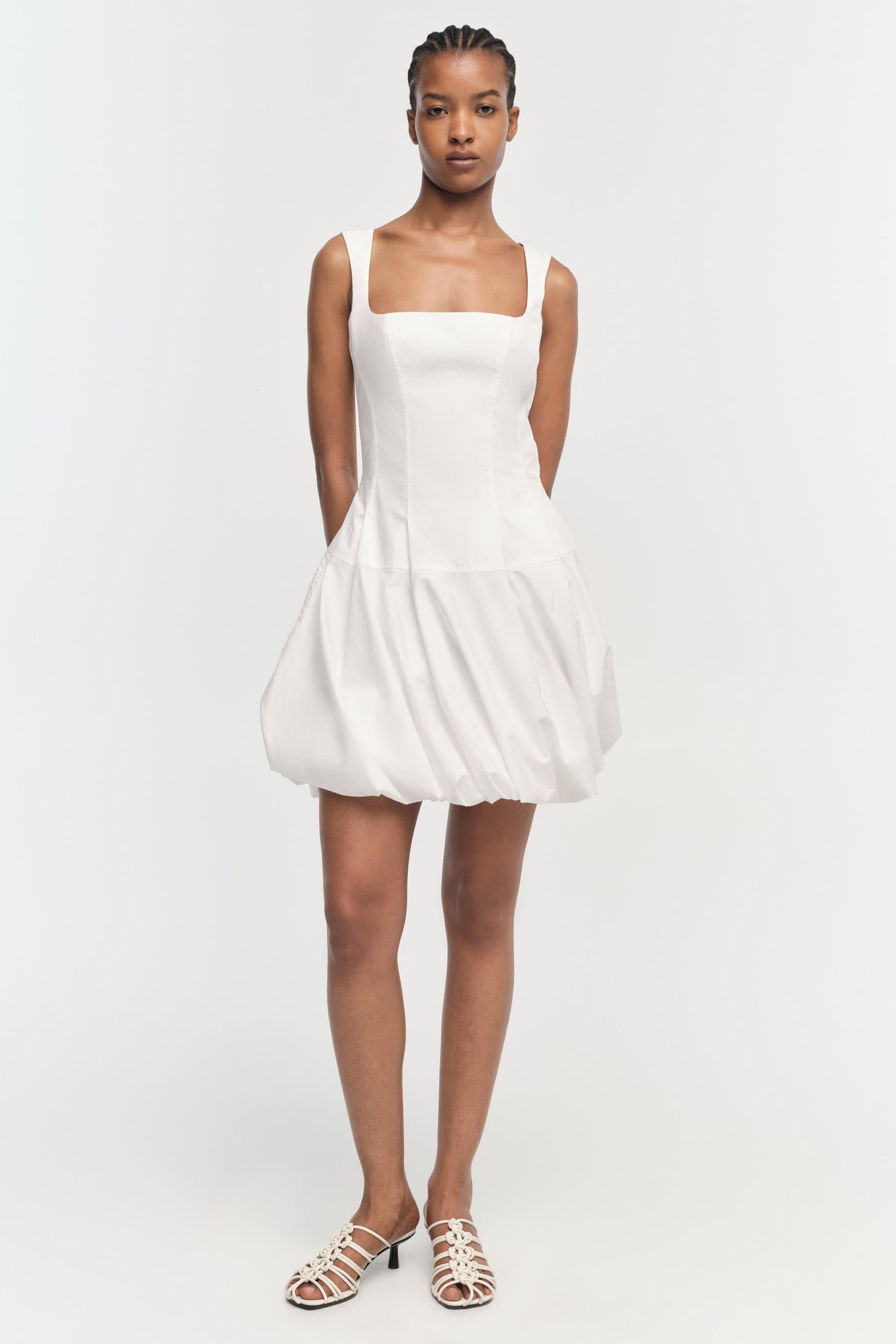 White sleeveless mini dress with square neckline and bubble hem skirt.