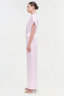 Woman wearing light pink wide-leg pants with a matching short-sleeve top, shown in profile view.