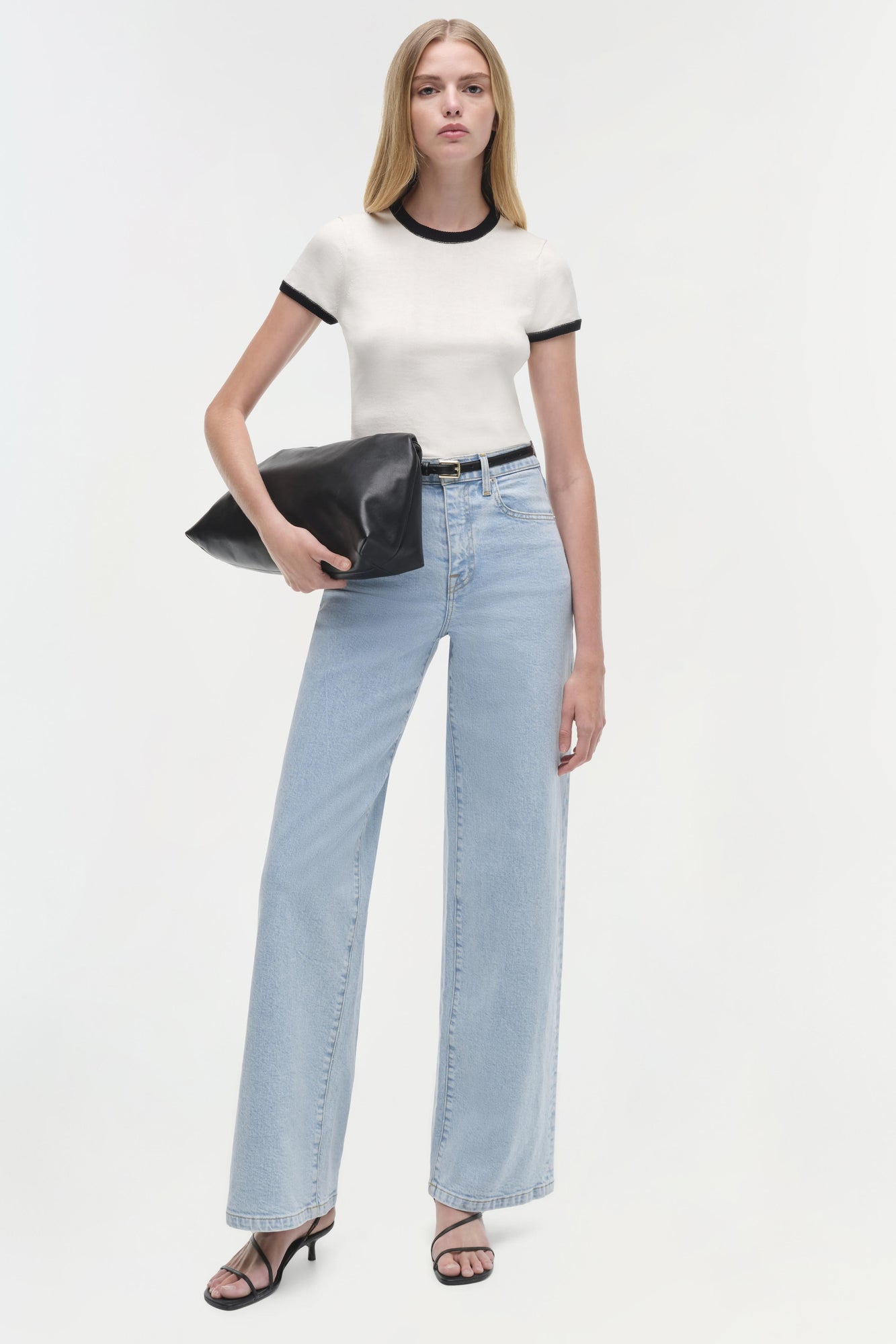 White short-sleeve top with black neck and arm trim worn with light blue jeans.