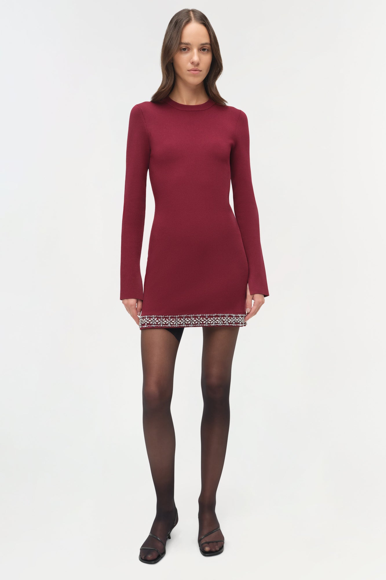 Burgundy knit mini dress with long sleeves and beaded trim detail at hem, modeled with black tights.