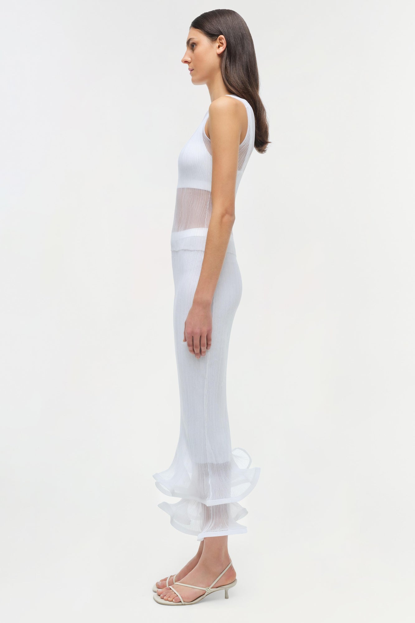 White ribbed sleeveless tank dress with sheer mesh panel at waist, modeled on woman in side view.