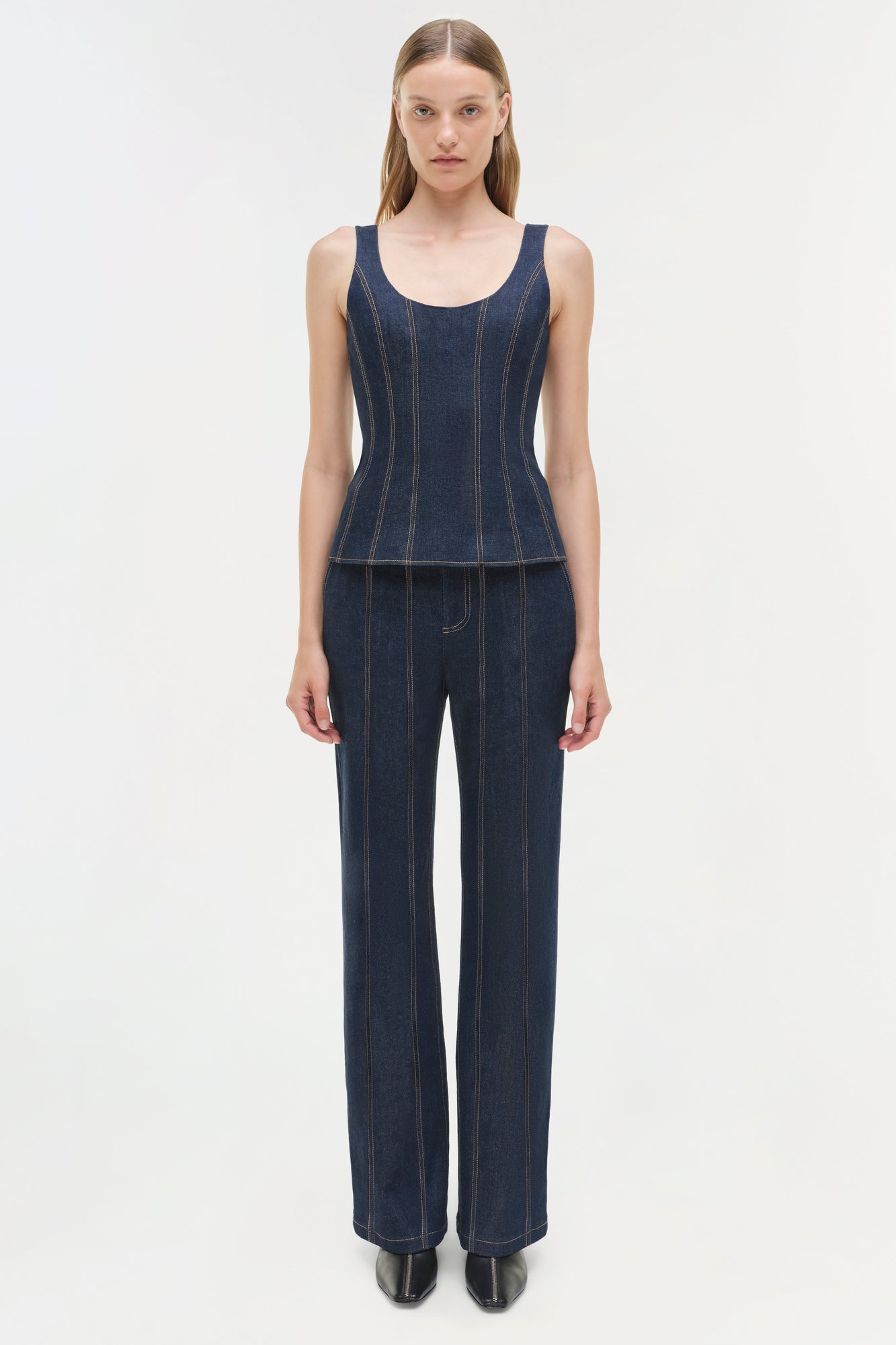 Woman wearing dark blue denim bustier top with vertical stitching and matching wide-leg denim pants.