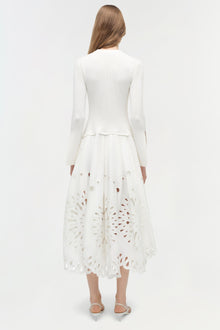 White knit midi dress with long sleeves and embroidered cutout details on the skirt, shown from the back.