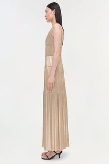 Beige pleated sleeveless gown with vertical striping and tiered panels, shown on model from side profile.