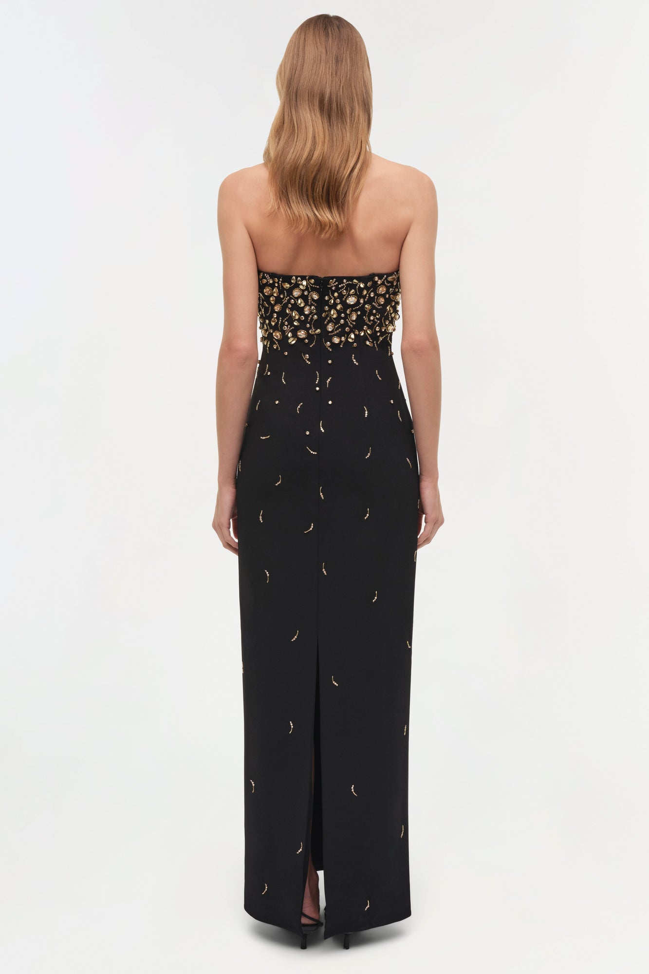 Black strapless gown with gold beaded bodice and scattered gold crescent moon details on skirt, rear view.