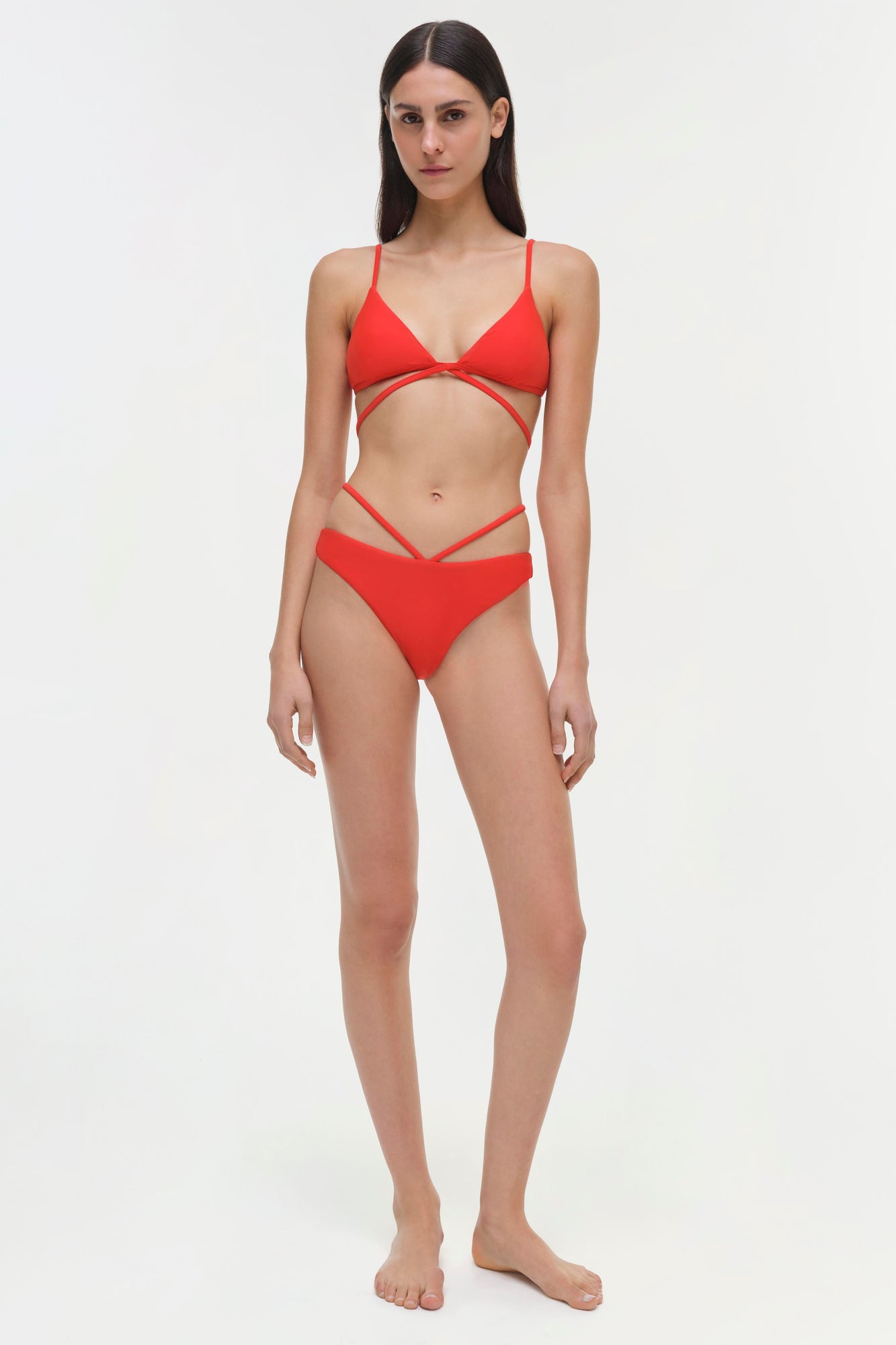 Red bikini top with thin shoulder straps, cutout detailing at chest and waist, worn with matching bottoms.