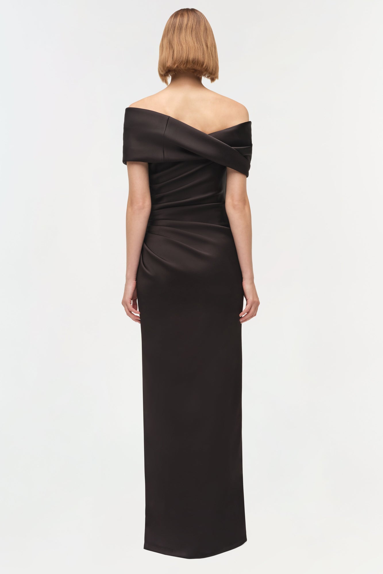 Black off-shoulder draped satin gown with ruched detailing and short sleeves, shown from back.