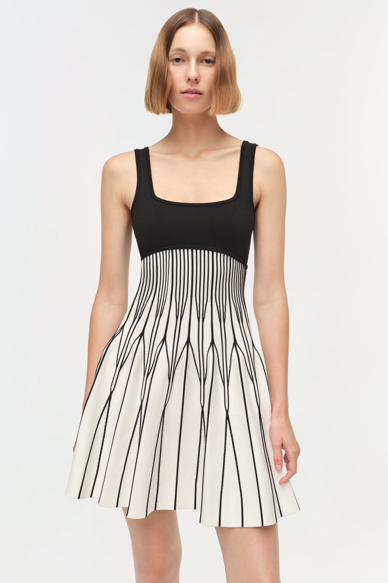 Black and cream knit mini dress with square neckline and vertical striped skirt detail.