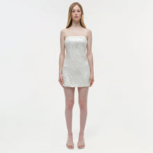 White sequined mini dress with thin straps on a model against a neutral background.