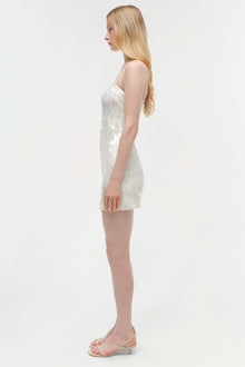 White sequined sleeveless mini dress with strappy neckline on model, shown side view.