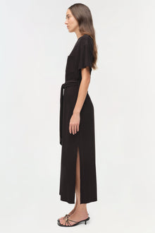 Black jersey t-shirt dress with short sleeves, drawstring waist, and front slit, shown on model in profile view.