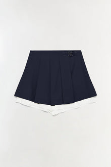 Navy pleated skort with white shorts underneath and two buckle straps at the waistband.