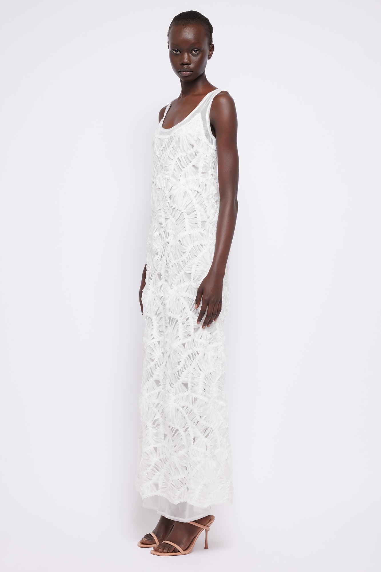 White sleeveless maxi dress with textured fringe pattern and scoop neckline.