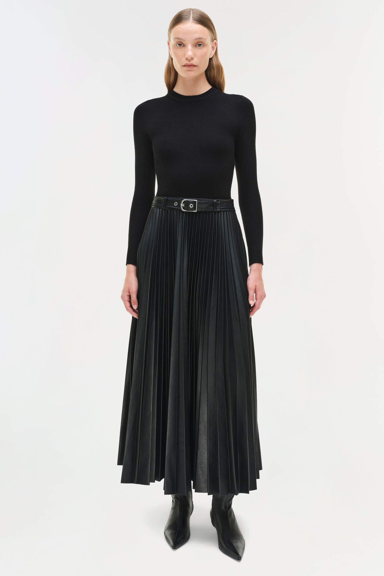 Black knit midi dress with long sleeves, pleated skirt, and belted waist worn with black boots.