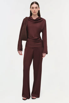 Burgundy satin top with draped cowl neckline and attached scarf detail paired with matching wide-leg trousers.