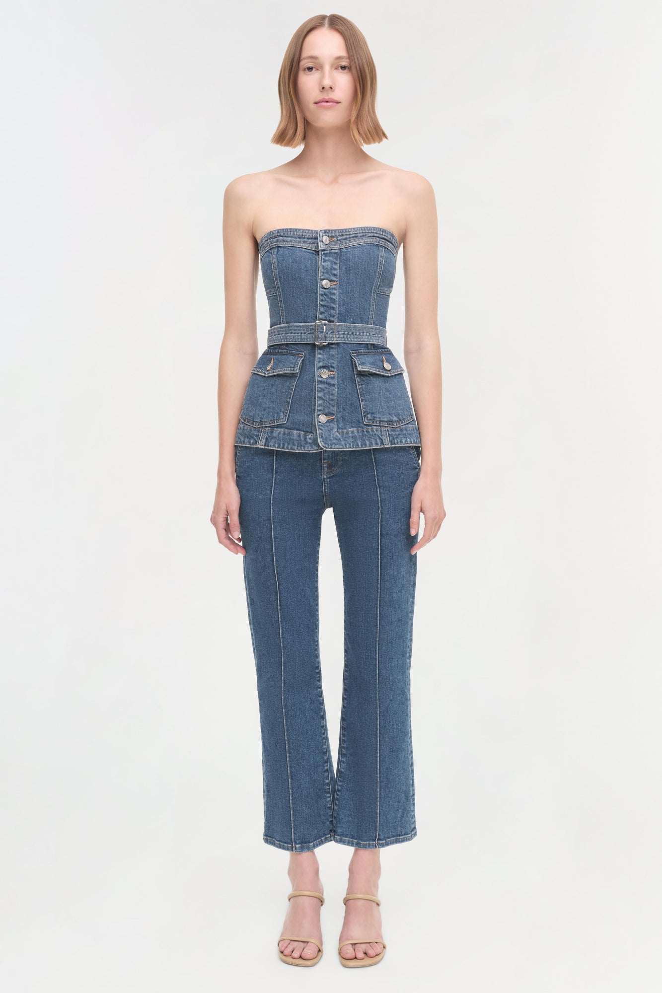 Woman wearing a blue denim strapless top with button front and cargo pockets, paired with matching cropped flare jeans.