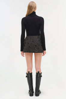Black mini skirt with allover sparkle embellishments, worn with black turtleneck and black boots.