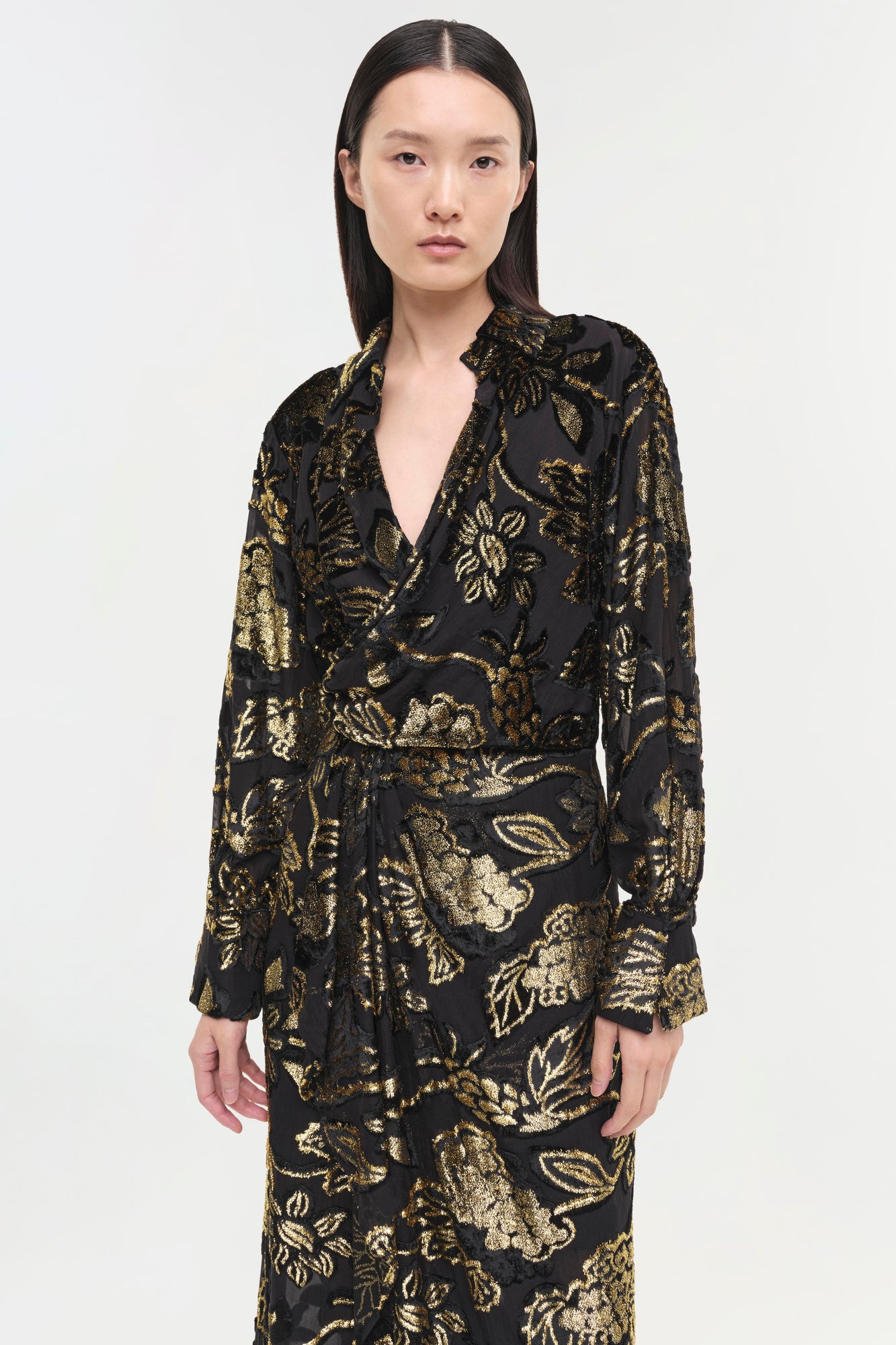 Black wrap dress with gold floral brocade pattern and long sleeves.