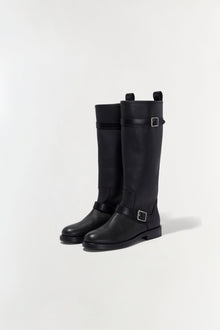Black leather knee-high boot with buckle straps and flat sole.