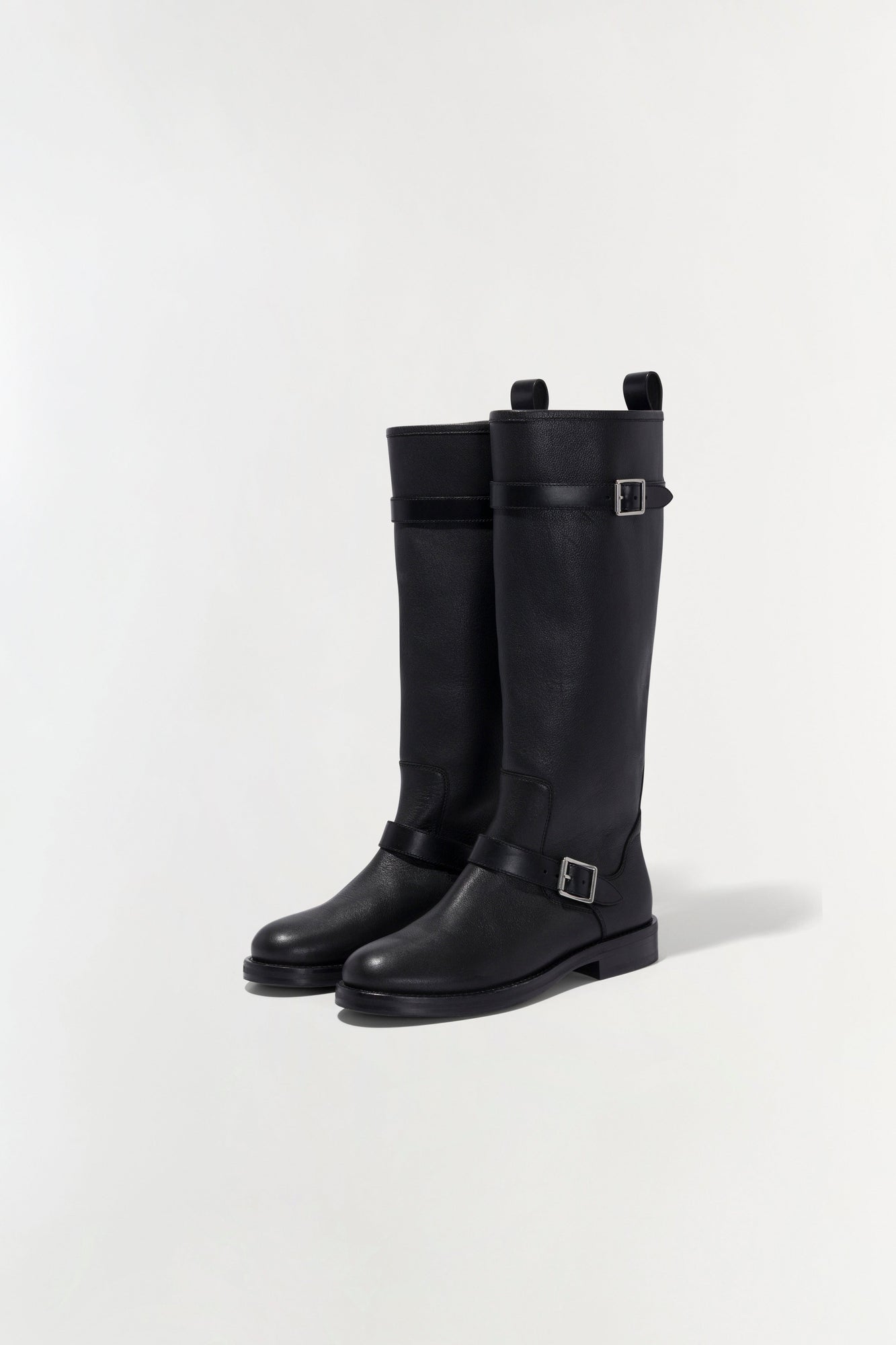 Black leather knee-high boot with buckle straps and flat sole.
