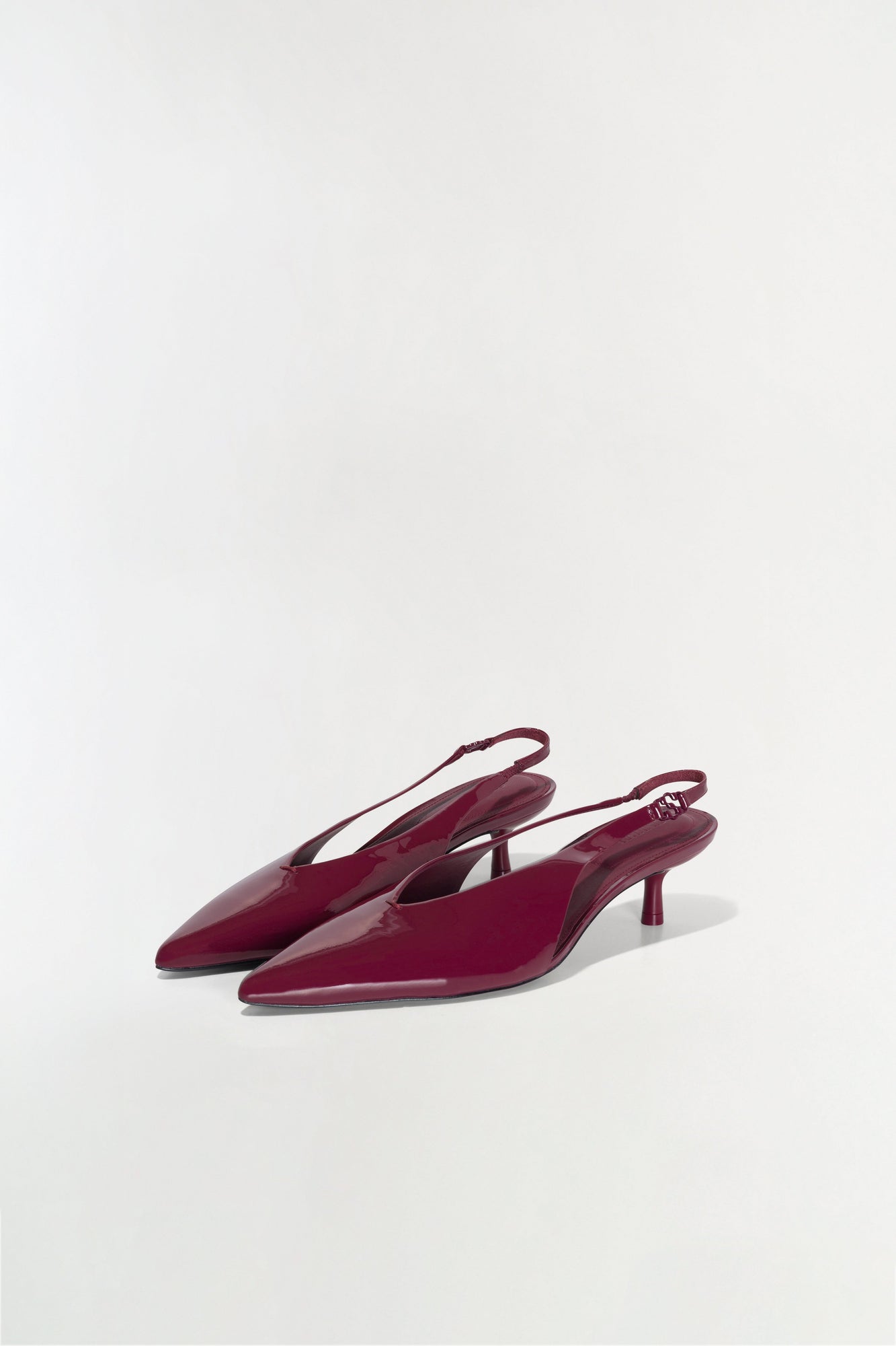 Burgundy patent leather slingback heels with pointed toes and thin kitten heels, shown from a side angle.