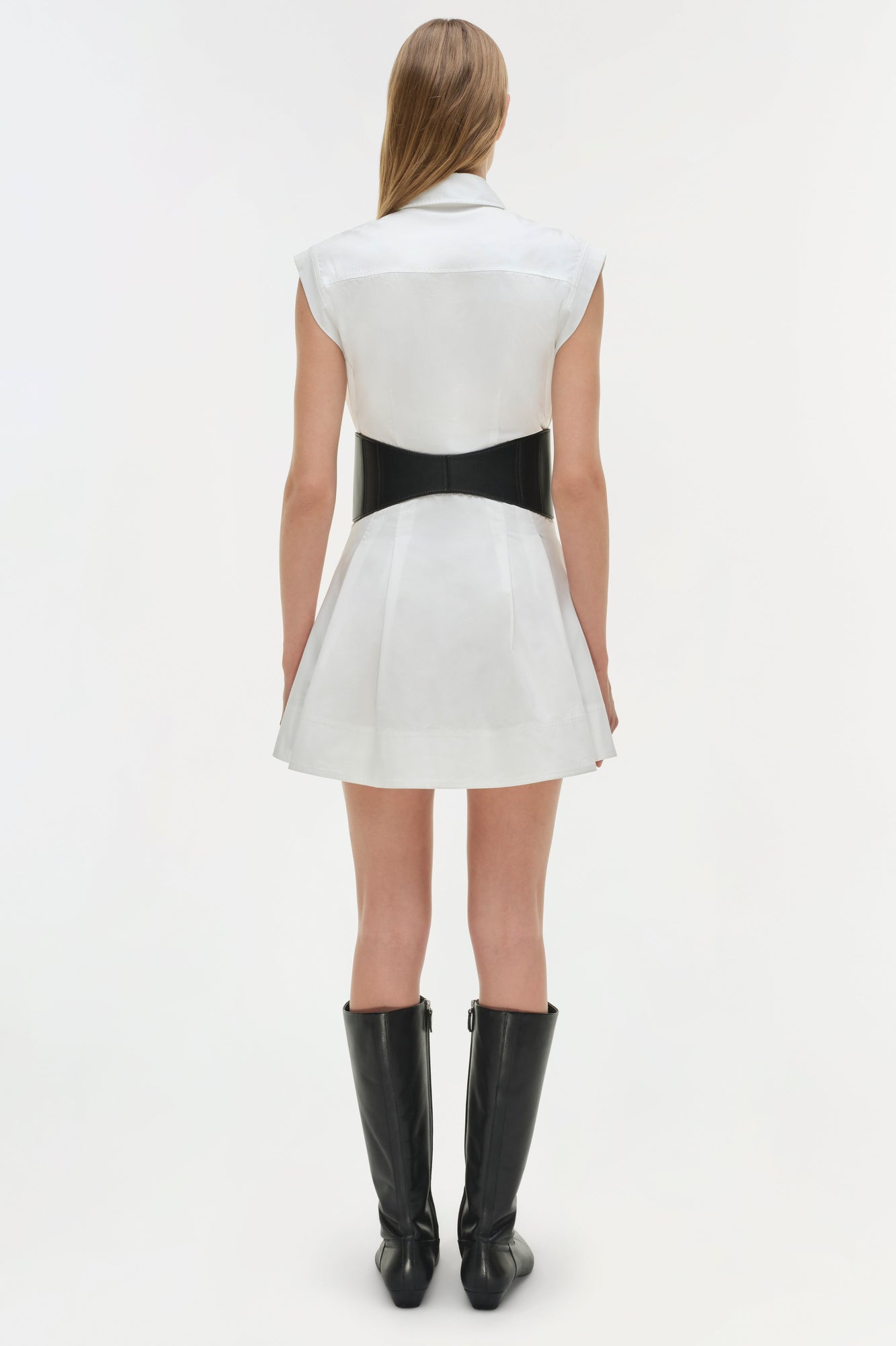 White cotton mini dress with black bow belt at waist, sleeveless collar neckline, and pleated skirt.