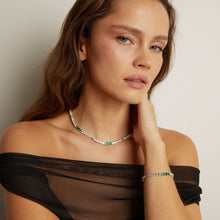 Woman wearing a necklace and bracelet with a neutral background