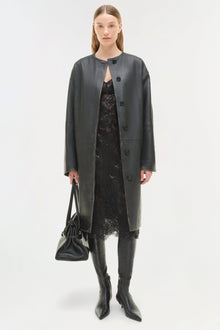 Dark gray leather coat worn open over black lace dress, paired with black leather boots and handbag.