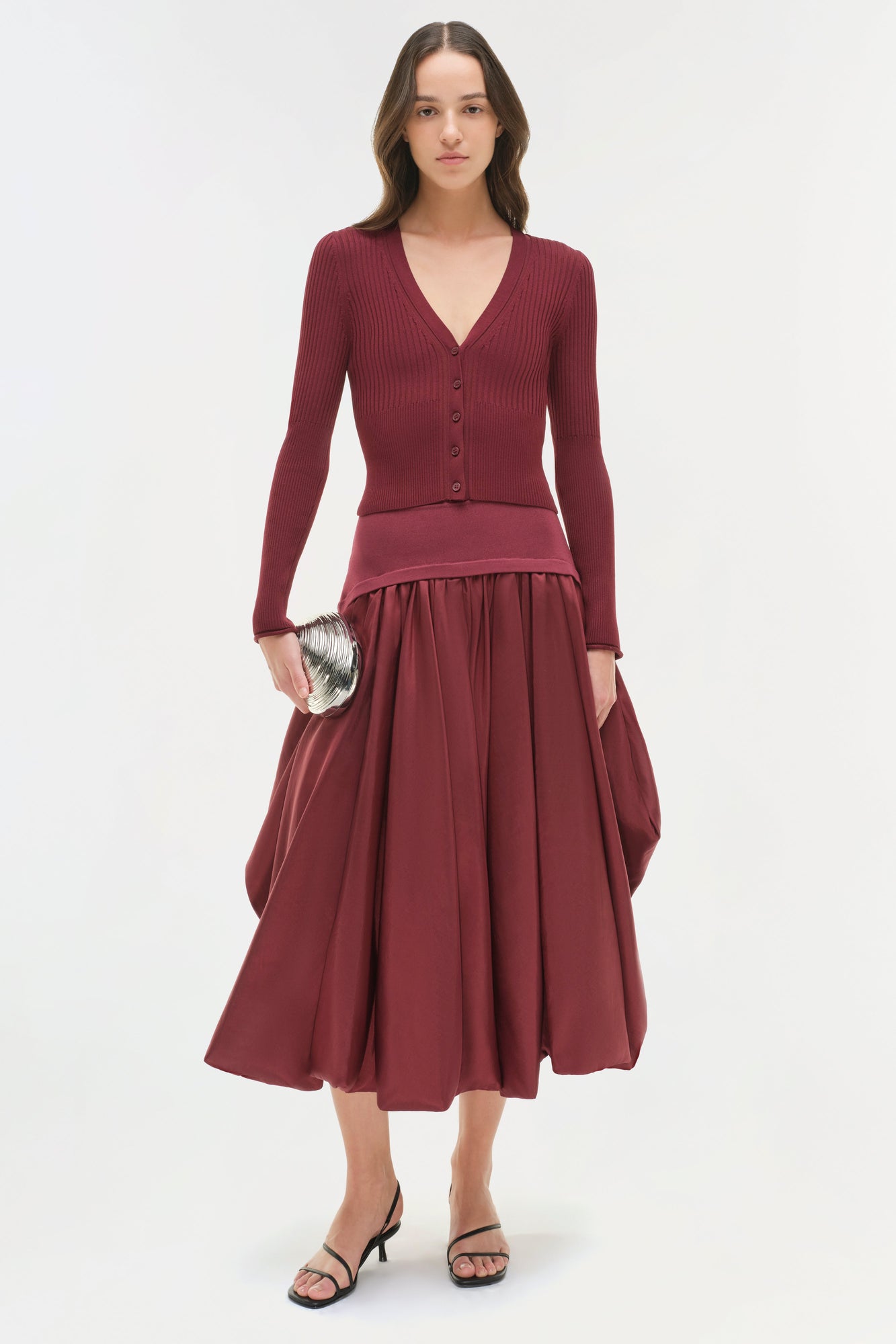 Woman wearing burgundy ribbed knit cardigan and full taffeta midi skirt with black strappy sandals.