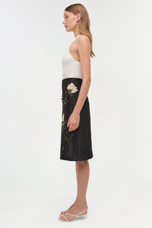 Black midi skirt with white floral jacquard pattern worn with white sleeveless top.