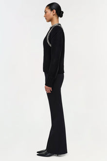 Black pullover sweater with beaded neckline trim, worn with black pants and black heels.