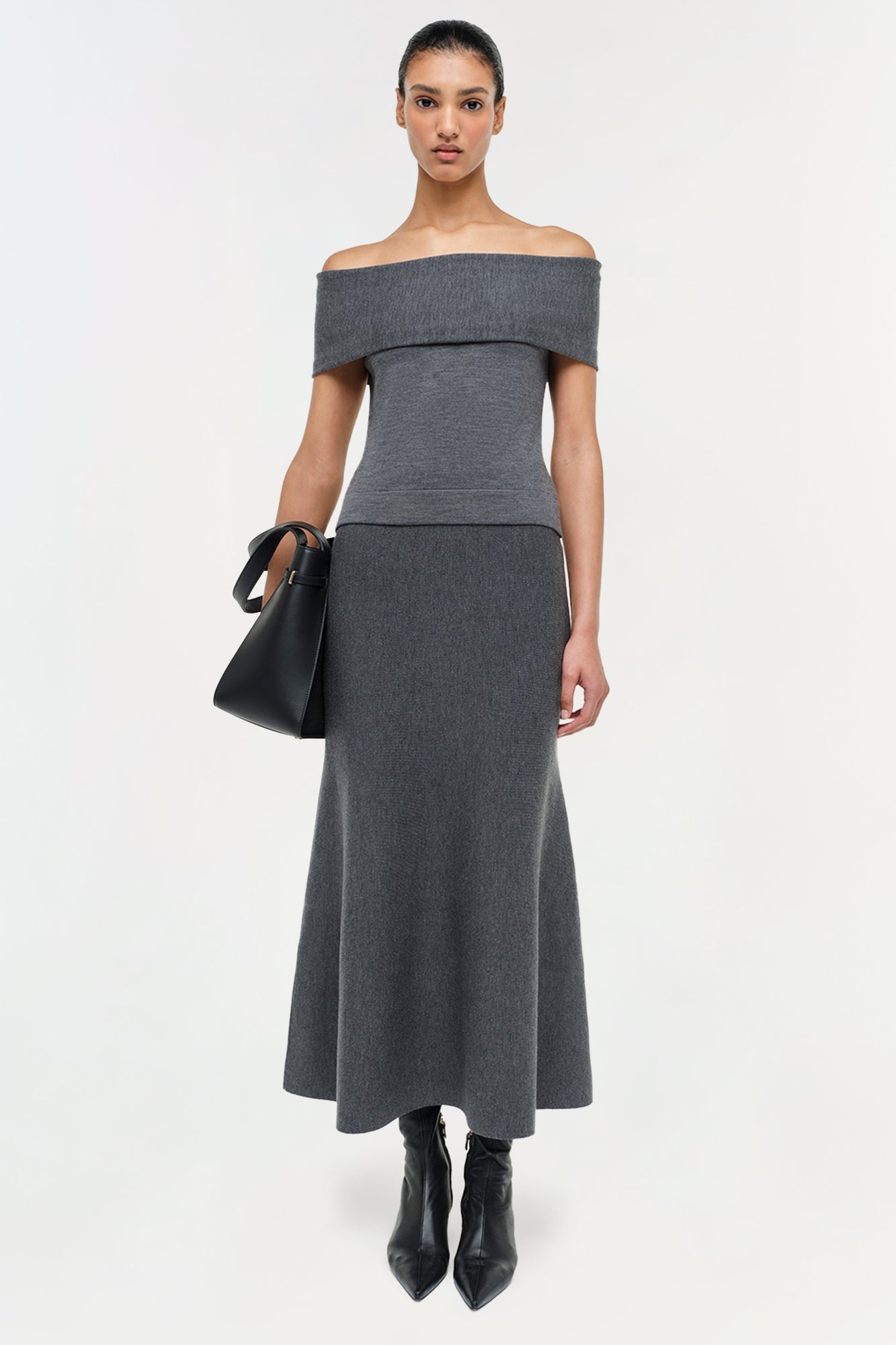 Charcoal gray wool off-shoulder top with folded neckline and fitted waist on model wearing black boots.