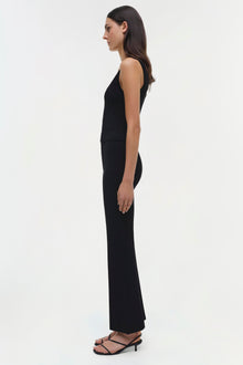 Woman wearing a black sleeveless tank top with matching wide-leg pants and black strappy heels, shown in side profile.