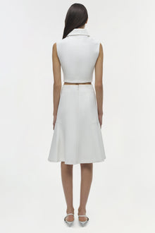 White sleeveless collared top with cutout at waist, worn with matching skirt, shown from back view.