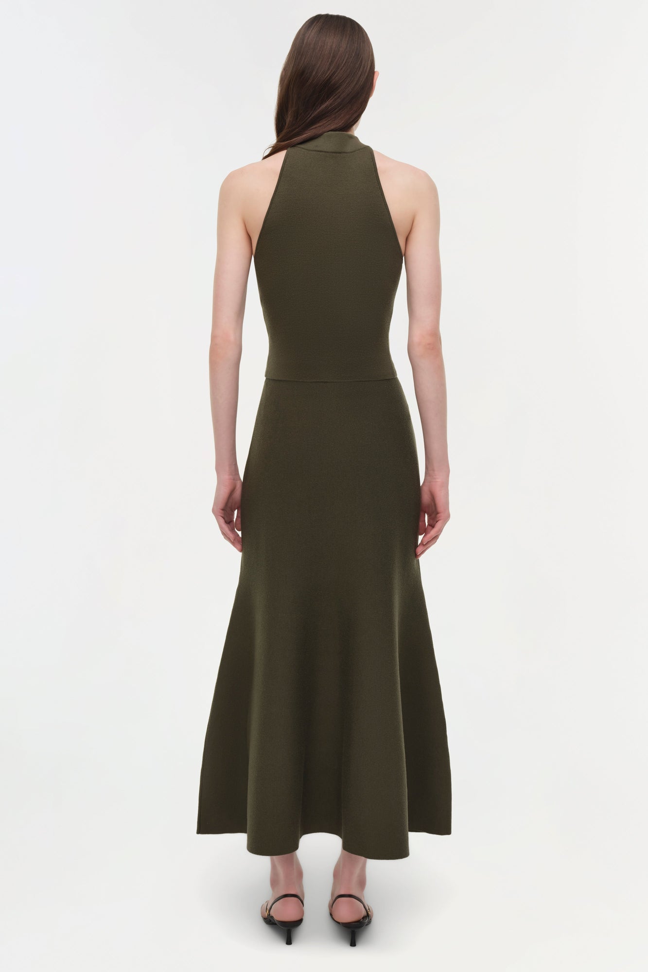 Woman wearing olive green wool midi skirt with matching halter top, back view.