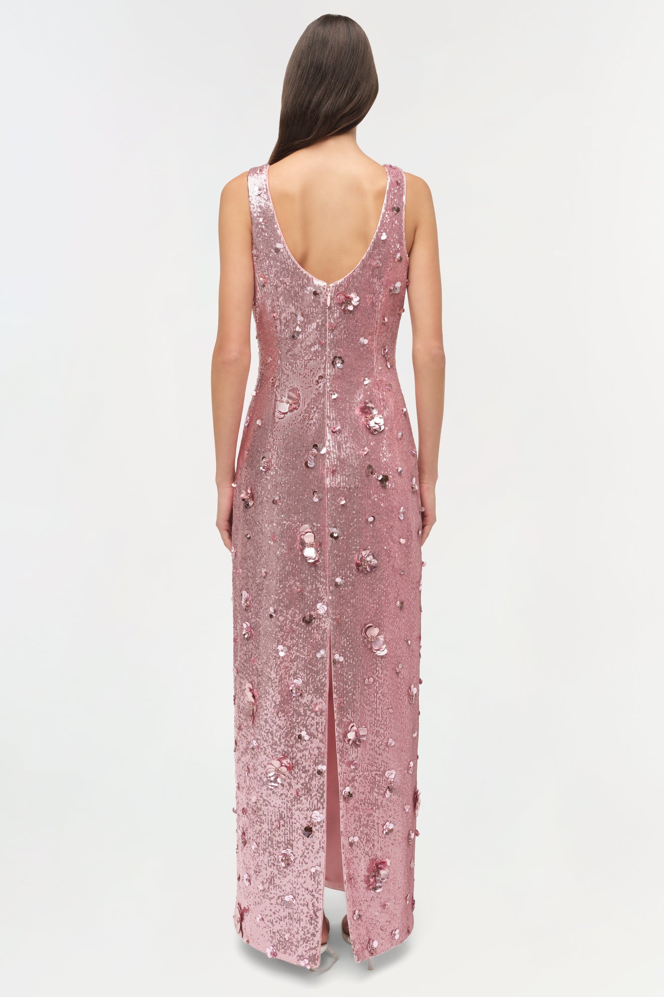 Sleeveless mauve sequin gown with low open back and high front slit, modeled from behind.