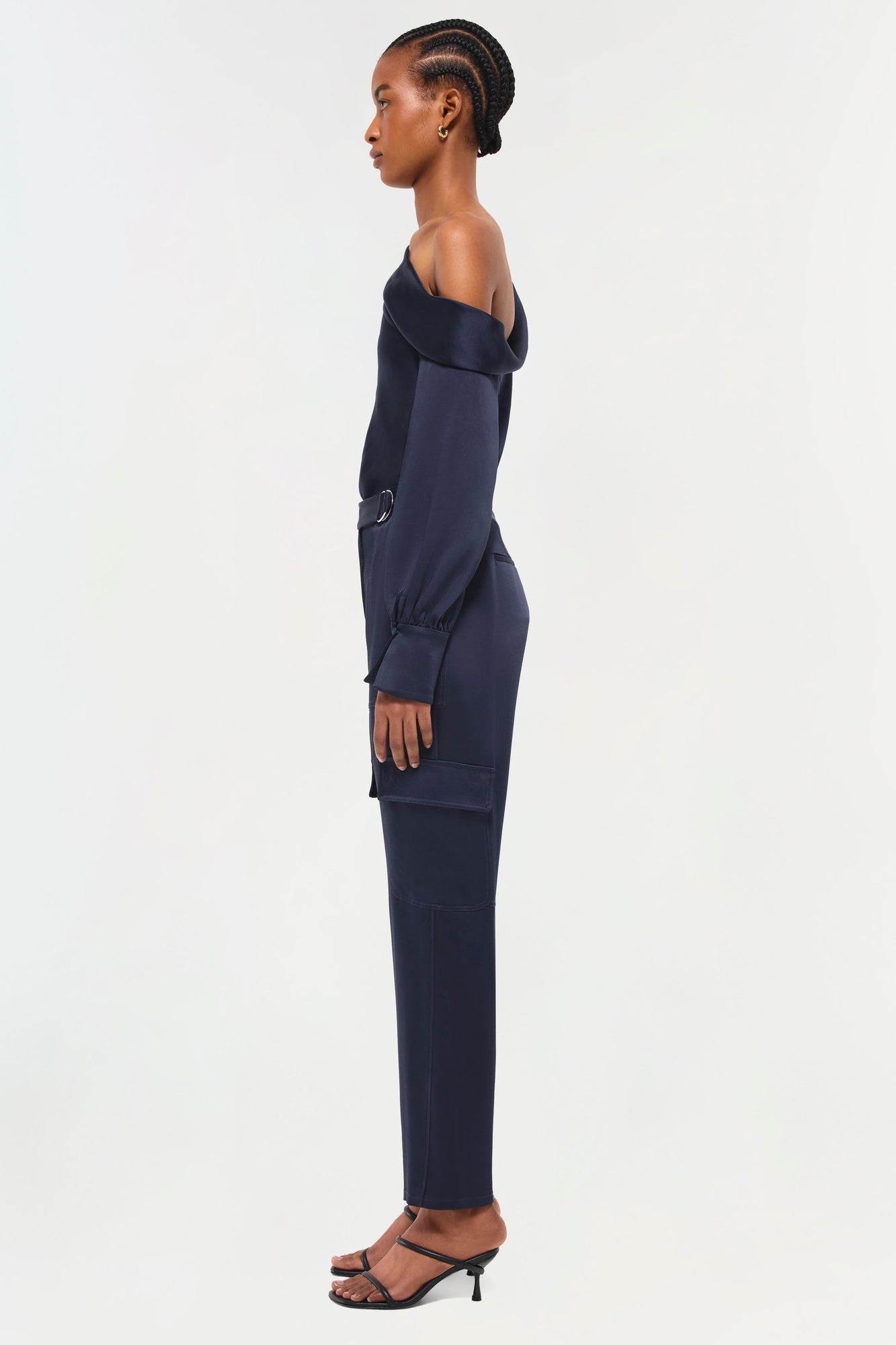 Navy off-shoulder jumpsuit with cargo pockets and long sleeves, shown on model in profile view.